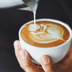 A cheeseburger on a background of gold bars and coins.