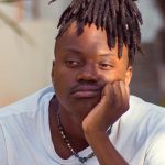 Rizzbot robot with arms out and cowboy hat on gesturing at camera