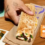 Taco Bell logo next to runner with Taco Bell wrappers on table