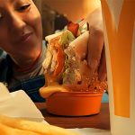 A woman dips her burger into a cheddar dipping sauce.