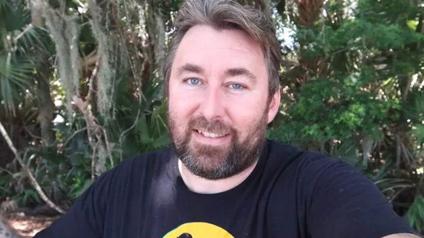 Adam The Woo in black and yellow shirt talking to camera