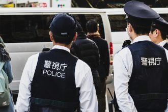 Two Japanese police officers stand on the street.