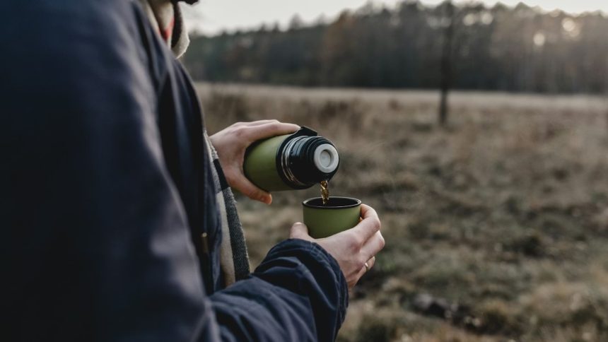 Person pouring drink through green thermos