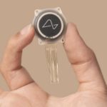 Neuralink chip being held up by hand