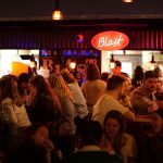 Bar fall of young drinkers with red sign on top of it