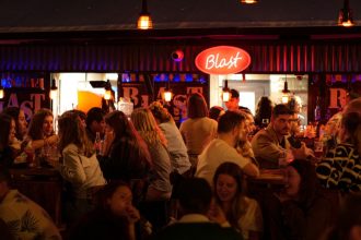 Bar fall of young drinkers with red sign on top of it
