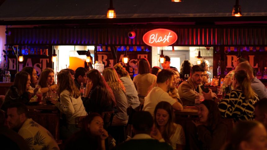 Bar fall of young drinkers with red sign on top of it