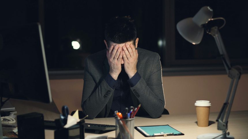 An office worker with his head in his hands.