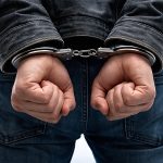 A photo of a man in handcuffs on a skating rink.