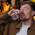 A photo of MrBeast chugging water against a background of flames and hot sauce bottles.