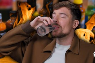 A photo of MrBeast chugging water against a background of flames and hot sauce bottles.