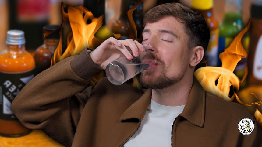 A photo of MrBeast chugging water against a background of flames and hot sauce bottles.