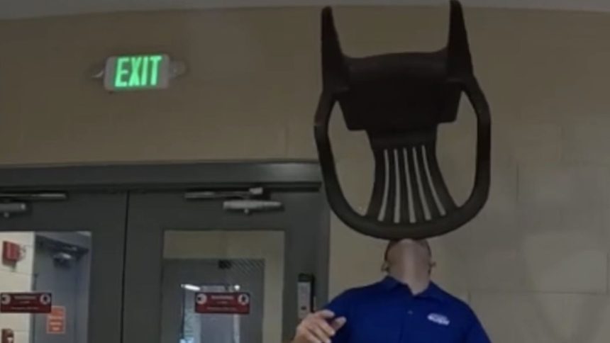 Man in blue shirt balancing green chair on chin