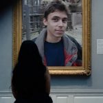 A woman sits in a museum looking at a picture frame with Jawed in 'Me at the zoo.'